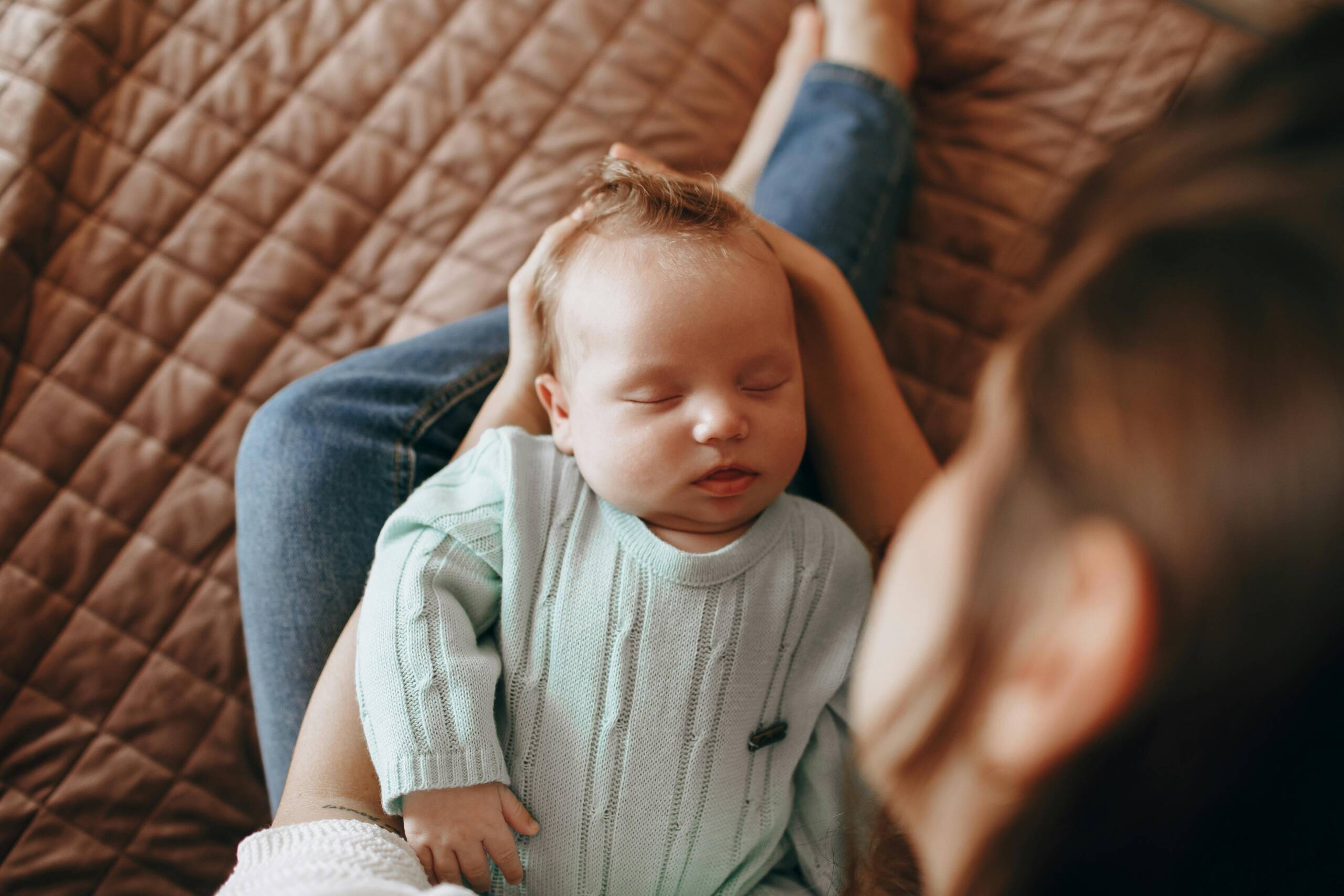 A serene scene of a baby peacefully sleeping in an adult's lap on a cozy quilt.